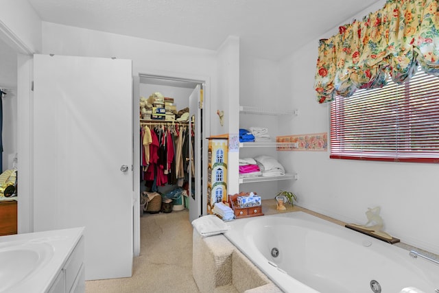 full bathroom with a tub with jets, a walk in closet, and vanity