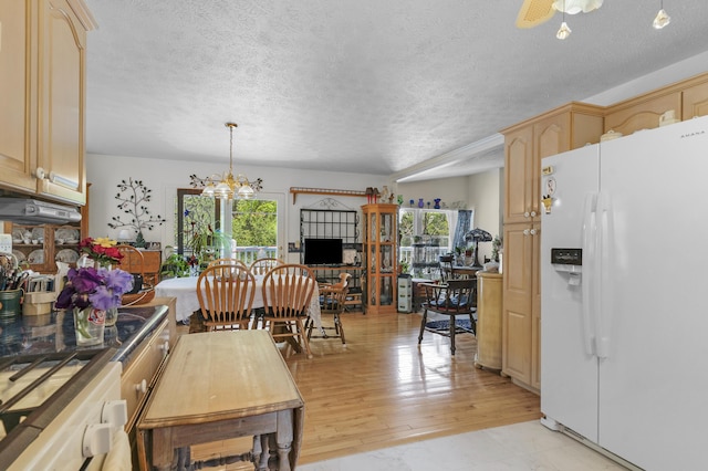 kitchen with a textured ceiling, light brown cabinetry, white refrigerator with ice dispenser, ceiling fan with notable chandelier, and light wood-style floors