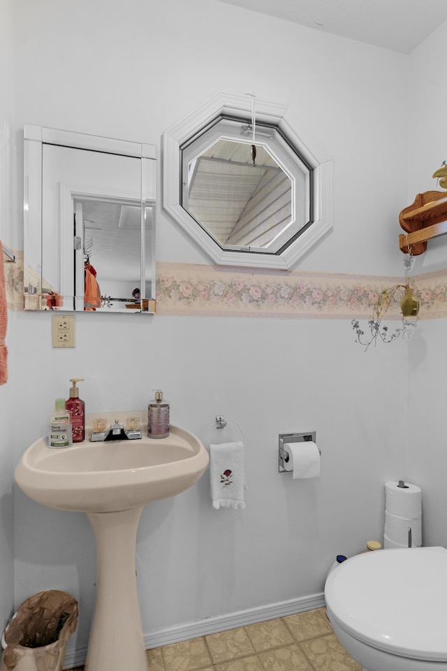 half bathroom featuring toilet and baseboards