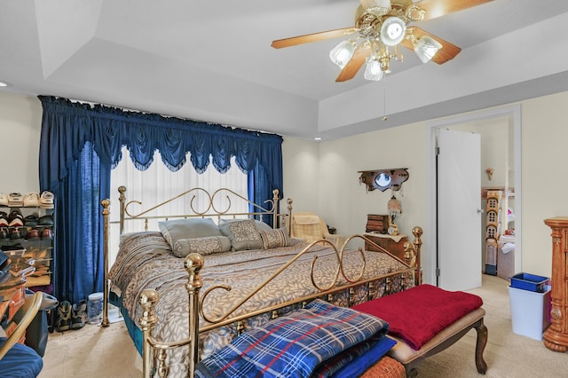 bedroom with carpet floors, a ceiling fan, and a raised ceiling