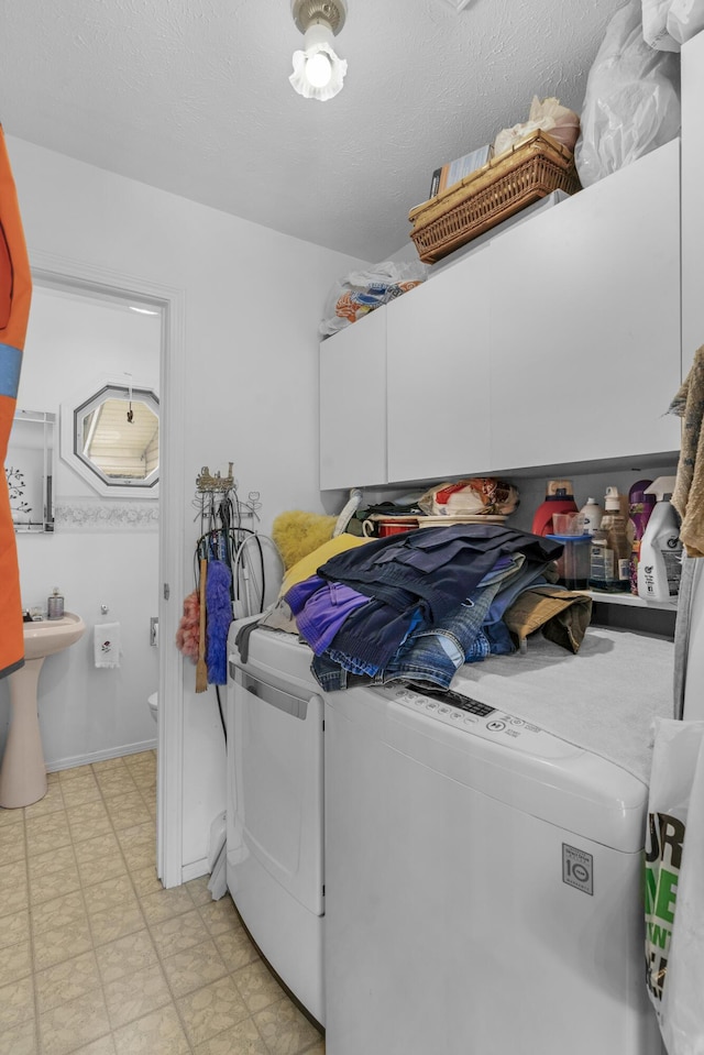 laundry area with washer and dryer, cabinet space, a sink, and light floors