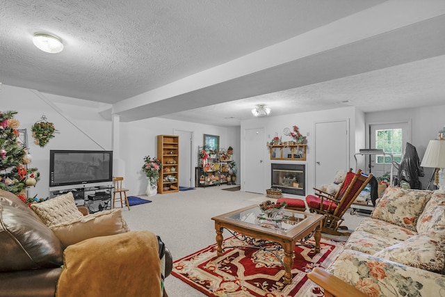 carpeted living room featuring a textured ceiling and a glass covered fireplace