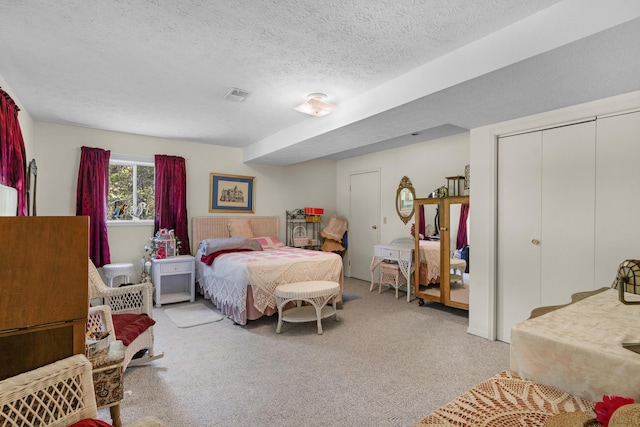 bedroom with light colored carpet, a textured ceiling, and visible vents