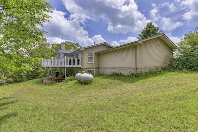 rear view of house with a yard, a wooden deck, and a chimney