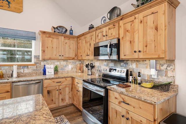 kitchen featuring stainless steel appliances, vaulted ceiling, decorative backsplash, light brown cabinets, and dark wood-type flooring