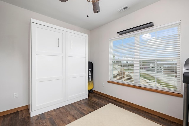 bedroom with dark wood-style floors, baseboards, visible vents, a ceiling fan, and a closet