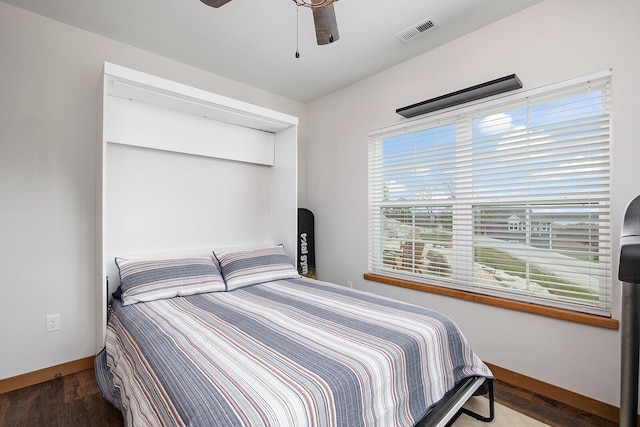 bedroom featuring baseboards, wood finished floors, visible vents, and ceiling fan