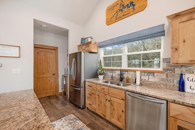 kitchen featuring appliances with stainless steel finishes, tasteful backsplash, a sink, and light brown cabinetry