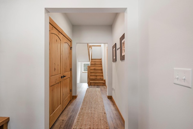 corridor with stairway, baseboards, and light wood finished floors