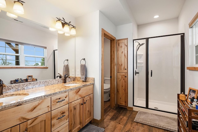 bathroom featuring wood finished floors, toilet, a stall shower, and a sink