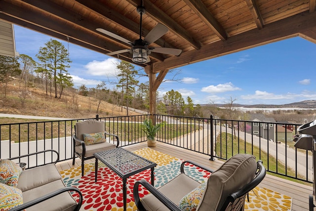 wooden terrace with ceiling fan, an outdoor hangout area, and a mountain view