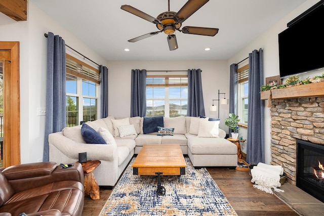 living room featuring recessed lighting, dark wood finished floors, a stone fireplace, and ceiling fan