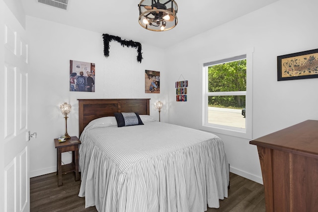 bedroom featuring a chandelier, visible vents, baseboards, and dark wood-style flooring