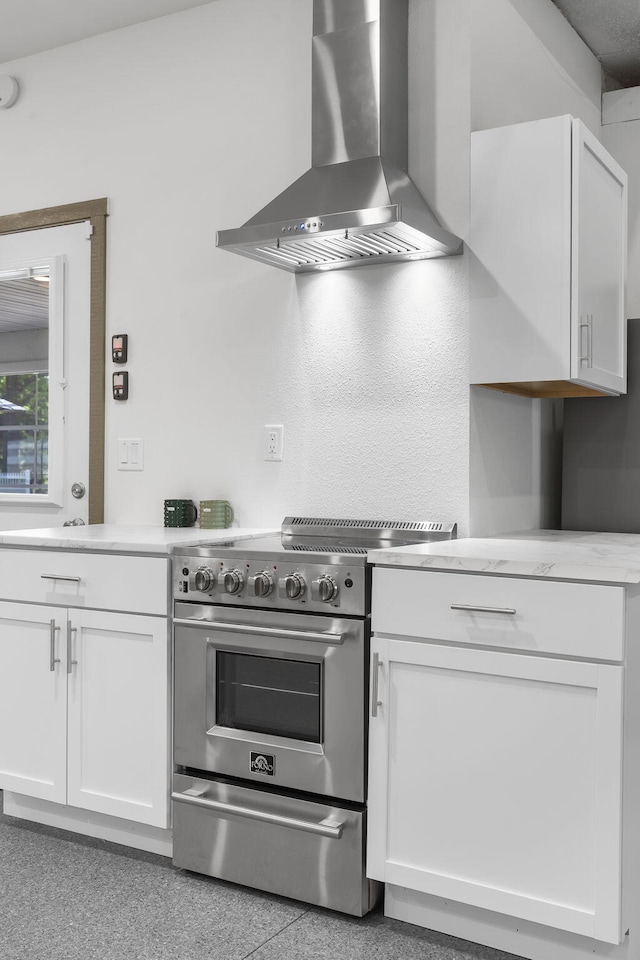 kitchen with white cabinets, wall chimney exhaust hood, high end stove, and light countertops