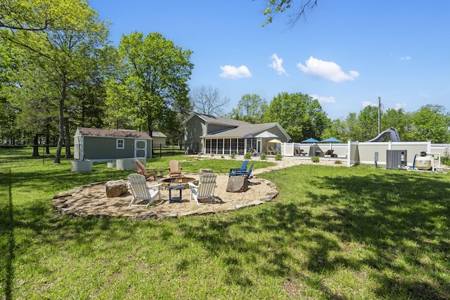 view of yard with a shed, an outdoor fire pit, a fenced backyard, an outdoor structure, and a patio