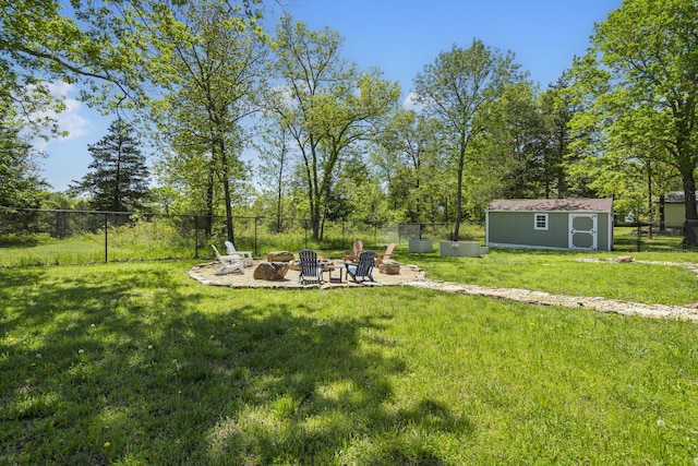view of yard with a storage shed, an outbuilding, an outdoor fire pit, and fence