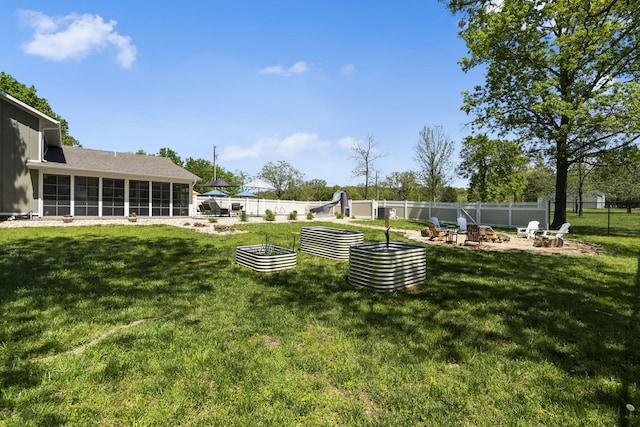view of yard with a fenced backyard, a fire pit, and a sunroom