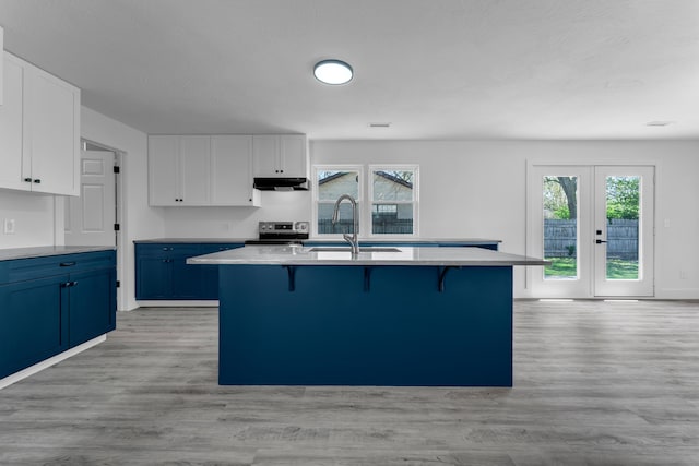 kitchen with a wealth of natural light, a sink, a kitchen bar, white cabinetry, and blue cabinetry