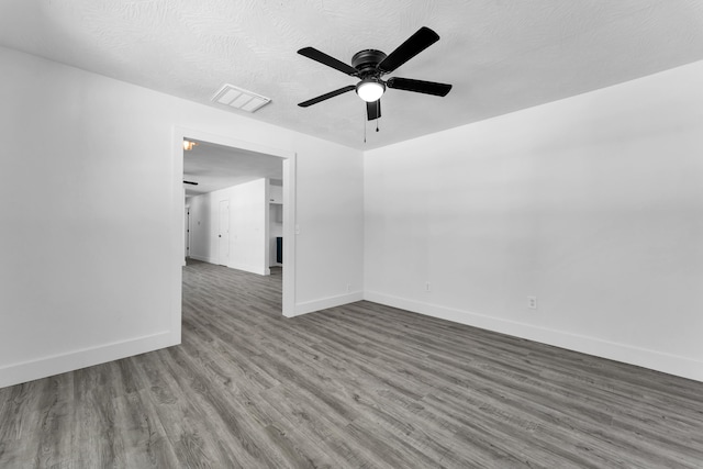 empty room featuring ceiling fan, baseboards, visible vents, and wood finished floors