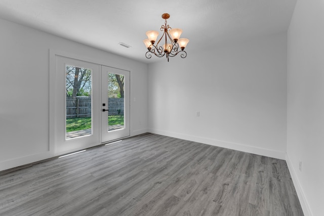 spare room with a chandelier, baseboards, french doors, and wood finished floors