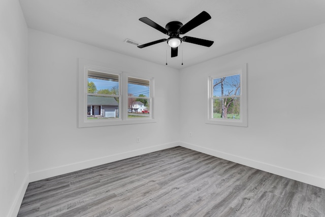 empty room with baseboards, visible vents, a ceiling fan, and wood finished floors
