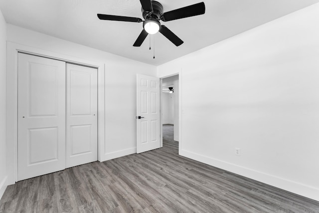 unfurnished bedroom with baseboards, a closet, ceiling fan, and wood finished floors