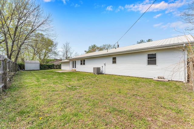 rear view of property with cooling unit, a lawn, an outdoor structure, a fenced backyard, and a shed