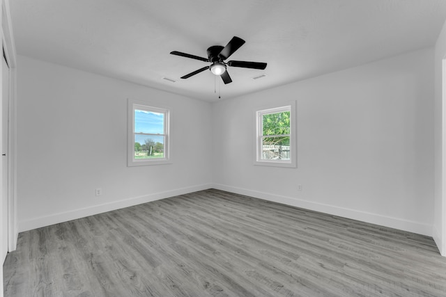 unfurnished room featuring a ceiling fan, visible vents, wood finished floors, and baseboards