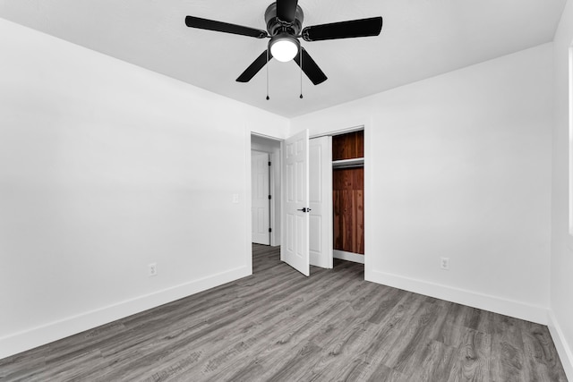 unfurnished bedroom with a closet, wood finished floors, baseboards, and ceiling fan