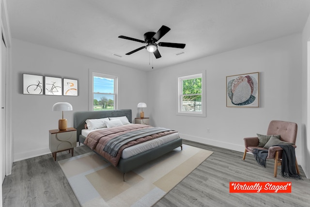 bedroom with wood finished floors, baseboards, visible vents, and multiple windows