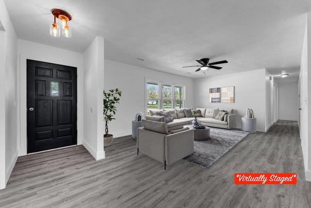 living area featuring baseboards, a ceiling fan, and wood finished floors