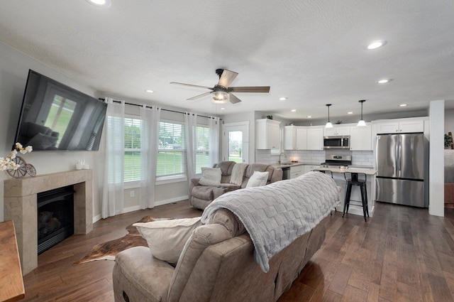 living area featuring baseboards, a ceiling fan, dark wood-type flooring, and recessed lighting