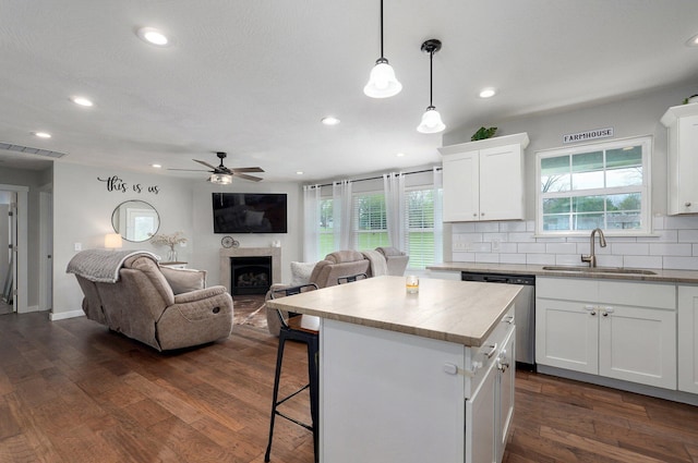 kitchen featuring a center island, a sink, a ceiling fan, dishwasher, and a breakfast bar