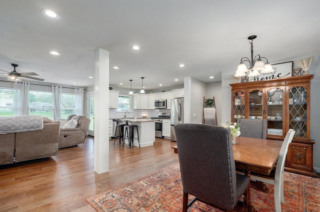 dining space featuring recessed lighting, light wood-style flooring, and ceiling fan with notable chandelier