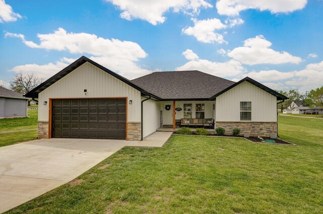 view of front of house featuring concrete driveway, stone siding, a shingled roof, an attached garage, and a front yard