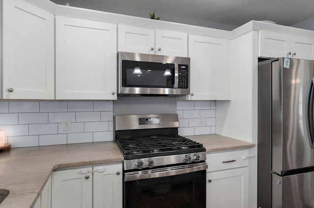 kitchen featuring light countertops, backsplash, white cabinetry, and appliances with stainless steel finishes