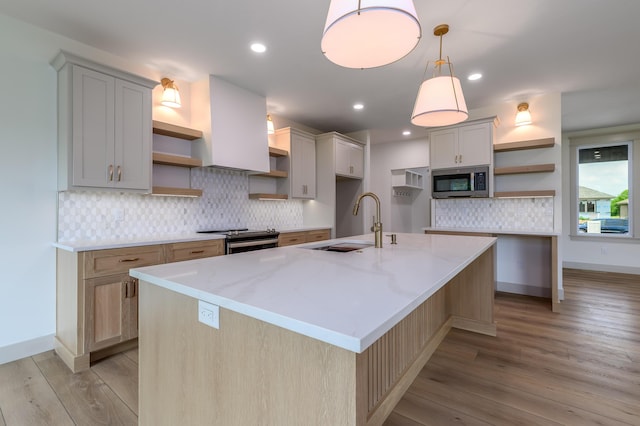 3800 W Broadmoor St, Springfield, MO 65807 - kitchen featuring open shelves, stainless steel appliances, light wood-style floors, tasteful backsplash, and a kitchen island with sink