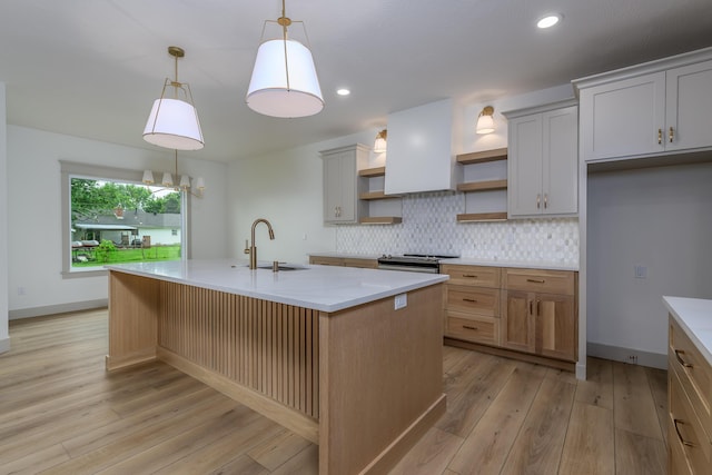 3800 W Broadmoor St, Springfield, MO 65807 - kitchen featuring open shelves, tasteful backsplash, light wood-type flooring, an island with sink, and pendant lighting