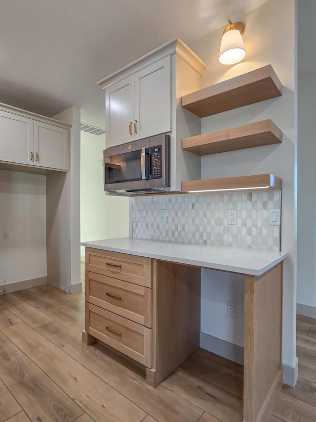 3800 W Broadmoor St, Springfield, MO 65807 - kitchen with stainless steel microwave, light wood-style floors, tasteful backsplash, and open shelves
