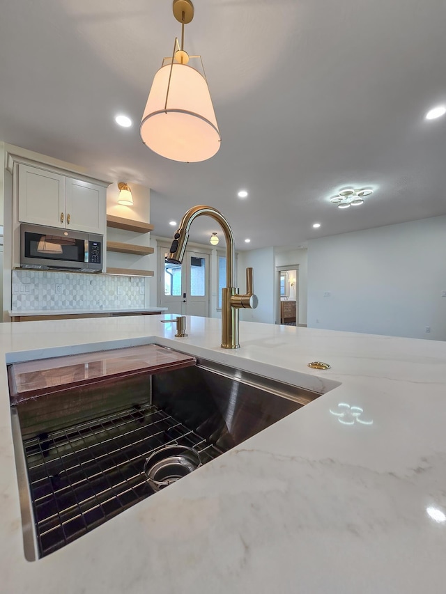 3800 W Broadmoor St, Springfield, MO 65807 - kitchen featuring stainless steel microwave, tasteful backsplash, light stone counters, hanging light fixtures, and recessed lighting