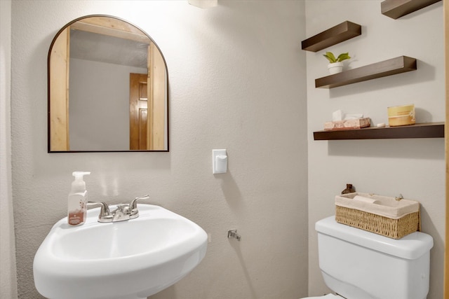 half bath featuring toilet and a sink