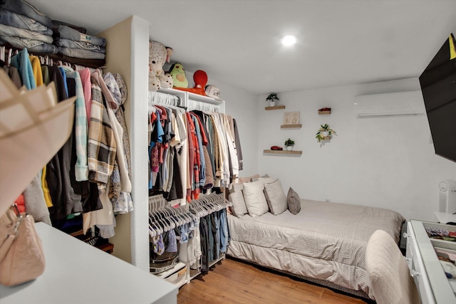 bedroom with recessed lighting, a wall unit AC, and wood finished floors