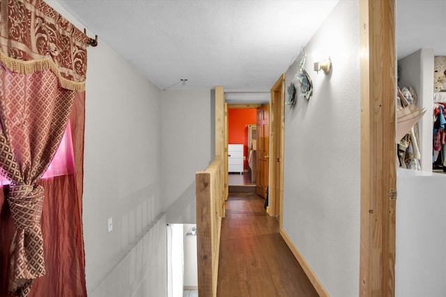hallway featuring an upstairs landing, wood finished floors, and baseboards