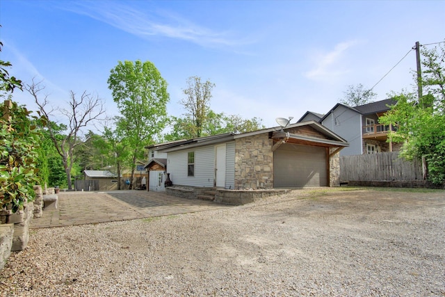 exterior space featuring fence, dirt driveway, and stone siding