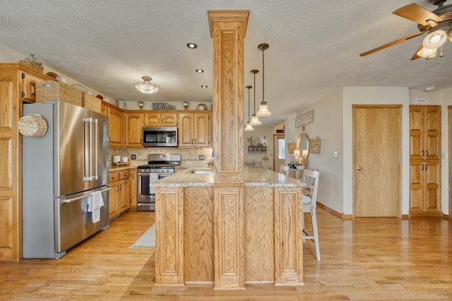 50 Tall Tree Dr, Strafford, MO 65757 - kitchen featuring ceiling fan, light wood-style floors, a peninsula, appliances with stainless steel finishes, and a breakfast bar area