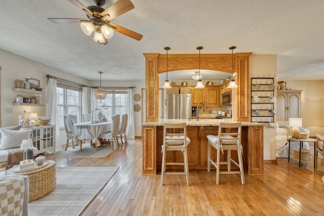 50 Tall Tree Dr, Strafford, MO 65757 - kitchen with a textured ceiling, light wood-type flooring, ceiling fan, light stone counters, and appliances with stainless steel finishes