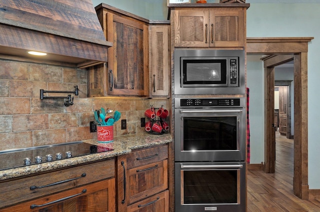 231 Cedar Stone, Ozark, MO 65721 - kitchen with light stone counters, wood finished floors, brown cabinetry, tasteful backsplash, and appliances with stainless steel finishes