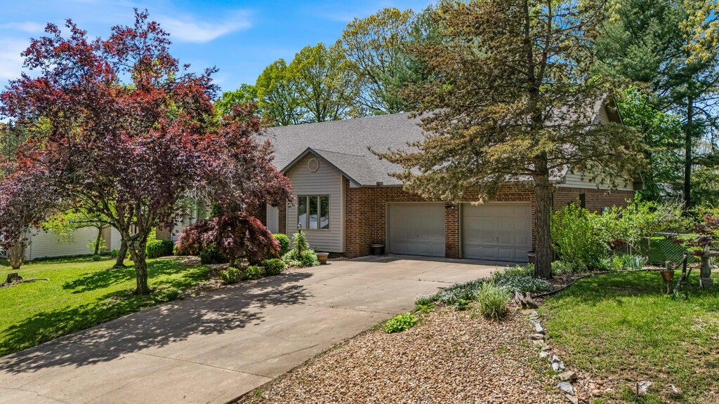 2811 Ginger Dr, West Plains, MO 65775 - obstructed view of property featuring a front lawn, brick siding, driveway, and a garage