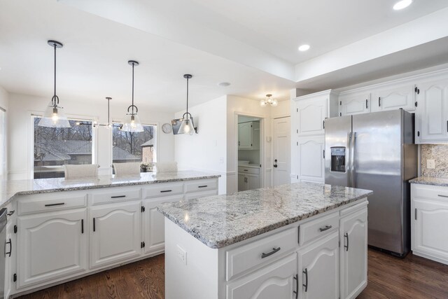 kitchen featuring dark wood finished floors, stainless steel refrigerator with ice dispenser, a center island, and tasteful backsplash