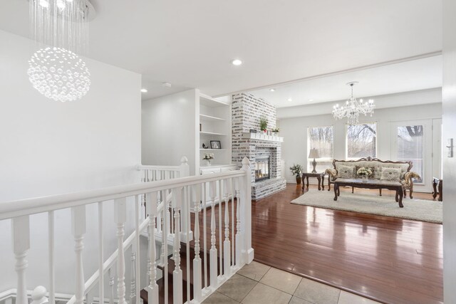 hallway featuring recessed lighting, tile patterned flooring, an inviting chandelier, an upstairs landing, and built in shelves
